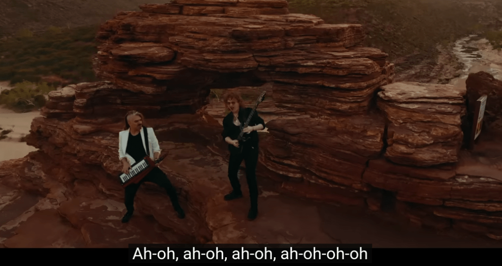 Danny with a keytar and Simone with a guitar on a mountain in Western Australia